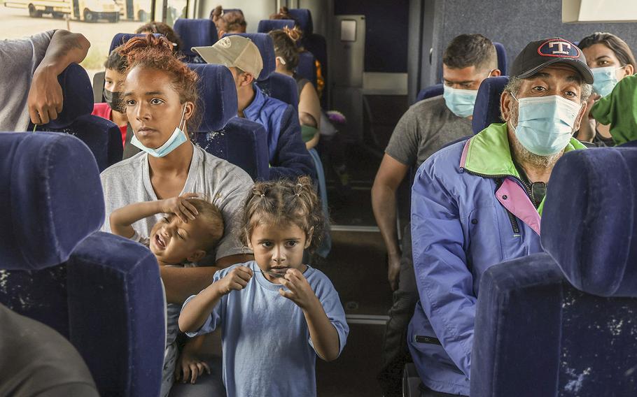 A bus full of people from Venezuela, Nicaragua and Cuba are shuttled away from Eagle Pass, Texas, on Sept. 18, 2022, as more asylum seekers were wading through the mostly-shallow waters of the Rio Grande from Piedras Negras, Mexico.