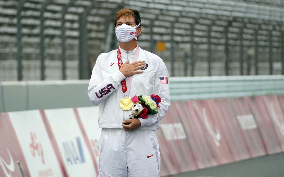 Army veteran Shawn Morelli stands for the U.S. national anthem after winning a gold medal in Paralympic road cycling at Fuji International Speedway outside Tokyo, Tuesday, Aug. 31, 2021.            