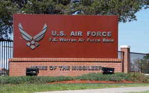 A red gate with silver text that reads “U.S. AIR FORCE/F.E. Warren Air Force Base.”