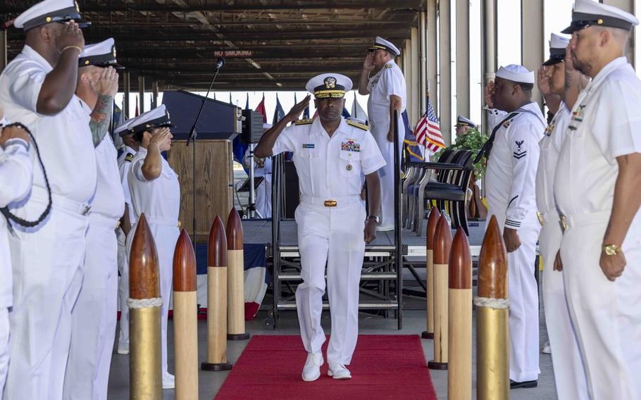 A Navy officer salutes sailors.
