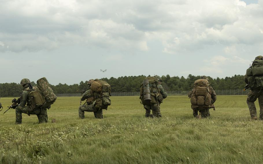 Troops crouch in a field.