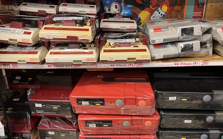 Classic game consoles, including the Nintendo Famicom, are stacked on shelves at Super Potato in Akihabara, Tokyo on November 30, 2021. 