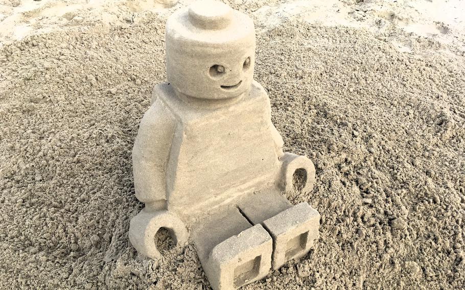 A sculpture of a Lego minifigure made of sand.