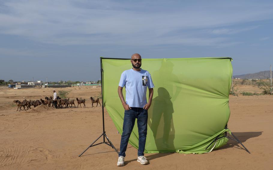 Divyendra Singh Jadoun, 31, a creator of deepfake content, poses against a green screen that he uses for generating videos using artificial intelligence in the deserts of Pushkar, India, on April 16, 2024. 