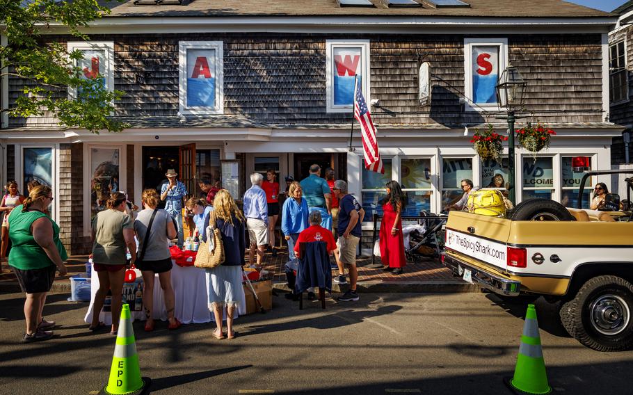 The exterior of the Wharf Pub in Martha’s Vineyard is seen with people in front of it during a “Jaws” 50th annivesary event. Each of the windows of the pub has a different letter of the word “Jaws.”
