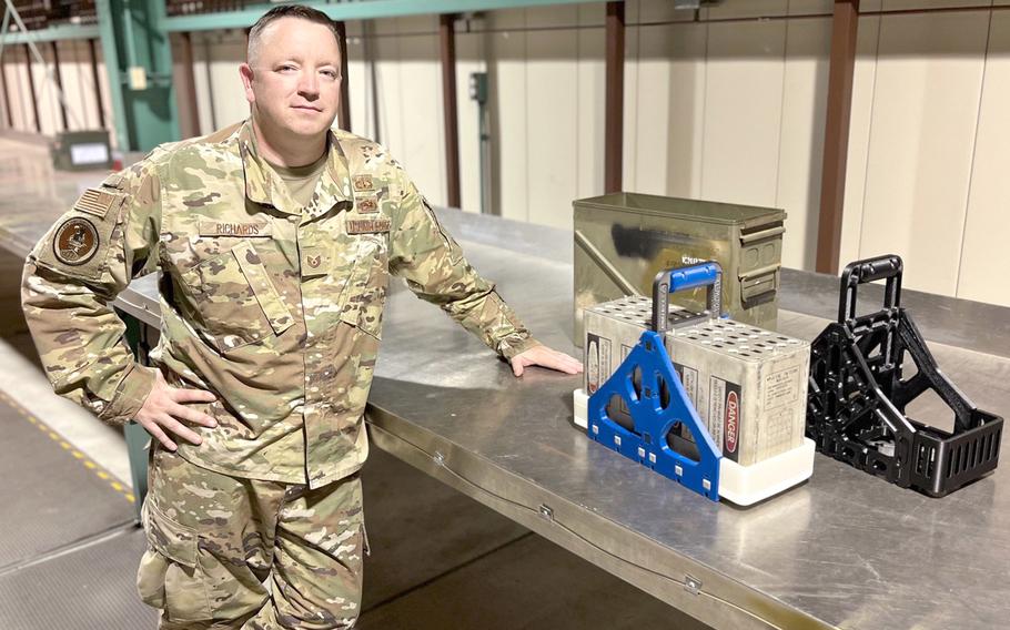 Tech Sgt. Nick Richards poses with the Hendy cradle prototype at Yokota Air Base, Japan, Sept. 16, 2022. The device is designed to make handling aircraft countermeasures safer.