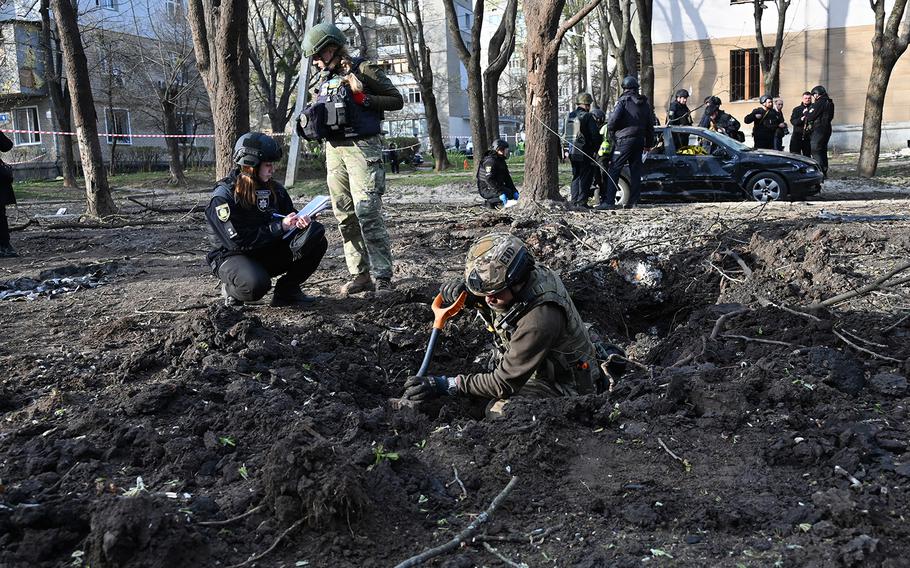 Ukrainian explosive technicians examine the site of the explosion after a missile strike in Kharkiv on April 6, 2024, amid the Russian invasion in Ukraine. 