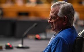 Tommy Tuberville, wearing a blue suit and seen from the side, sits at a table in a congressional hearing room.