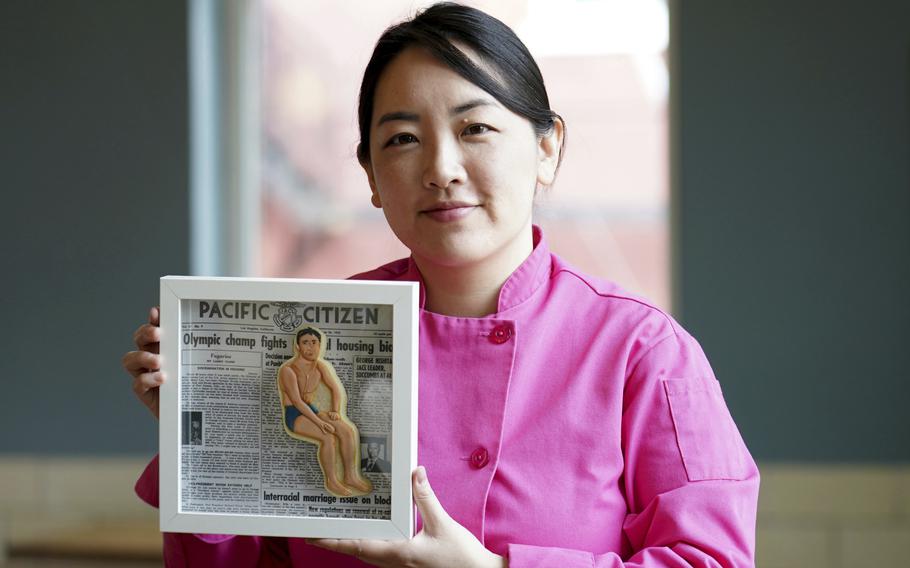 Jasmine Cho holds a framed cookie portrait of U.S. Olympian Sammy Lee, the first Asian American man to earn gold, in Pittsburgh, Pa., May 3. Cho, a Korean American self-described “cookie activist,” has gained fans over the last several years for her finely detailed cookie mugs of famous and forgotten figures. 