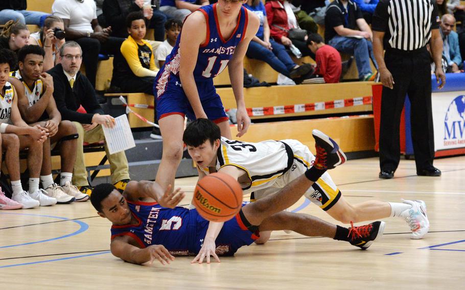 Ramstein’s Ky’Ron Hill passes to a teammate despite the pressure by Stuttgart’s John Gilliland in the boys Division I final at the DODEA-Europe basketball championships in Wiesbaden, Germany, Feb. 17, 2024. watching the action is Michael Gonzales. Stuttgart beat Ramstein 47-36.