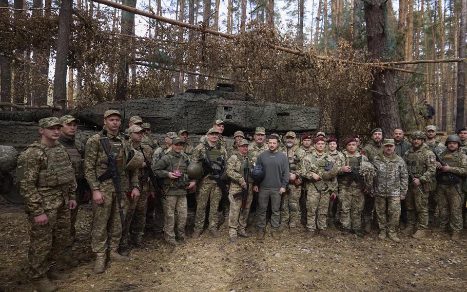 Ukrainian President Volodymyr Zelenskyy, center, stands with Ukrainian soldiers in front of a Leopard 2 tank on the front line in the Kharkiv region, Ukraine, on Oct. 3, 2023.