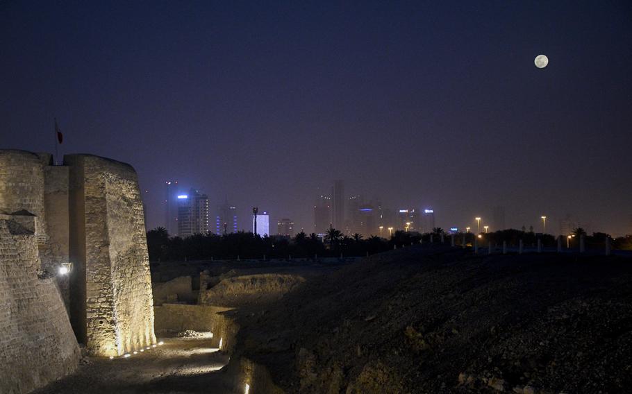 The moon rises over Manama, Bahrain, as floodlights illuminate the walls of the Qal'at al-Bahrain, also known as Bahrain Fort, on April 16, 2022.