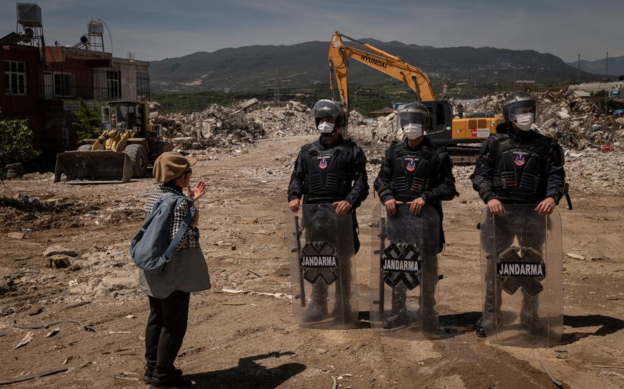 A resident who was part of a small group of protesters speaks to Turkish gendarmerie military police guarding the site of a rubble dump in Samandag on April 16, 2023