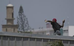 A demonstrator throws a rock at riot policemen during a protest at the Cheikh Anta Diop University campus in Dakar, Senegal, Thursday, June 1, 2023. Senegal opposition leader Ousmane Sonko was convicted Thursday of corrupting youth but acquitted on charges of raping a woman who worked at a massage parlor and making death threats against her. (AP Photo/Leo Correa)