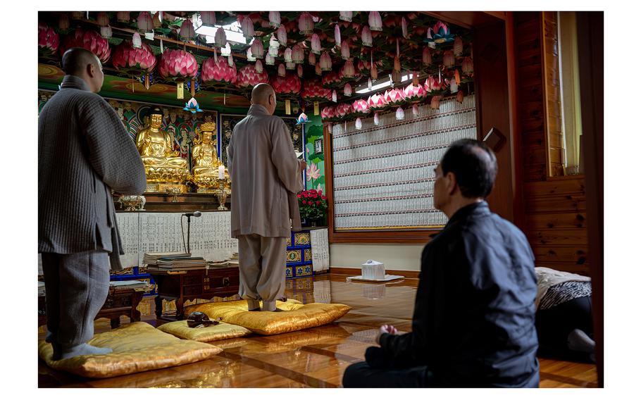 Lee Si-woo and Yoon Tae-yun pray at the temple in Busan where Lee Jong-wook's remains were taken to rest the night before the reinterring ceremony.