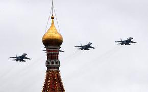 Four Russian fighter jets flying in formation, one of which is mostly obscured by a tower.