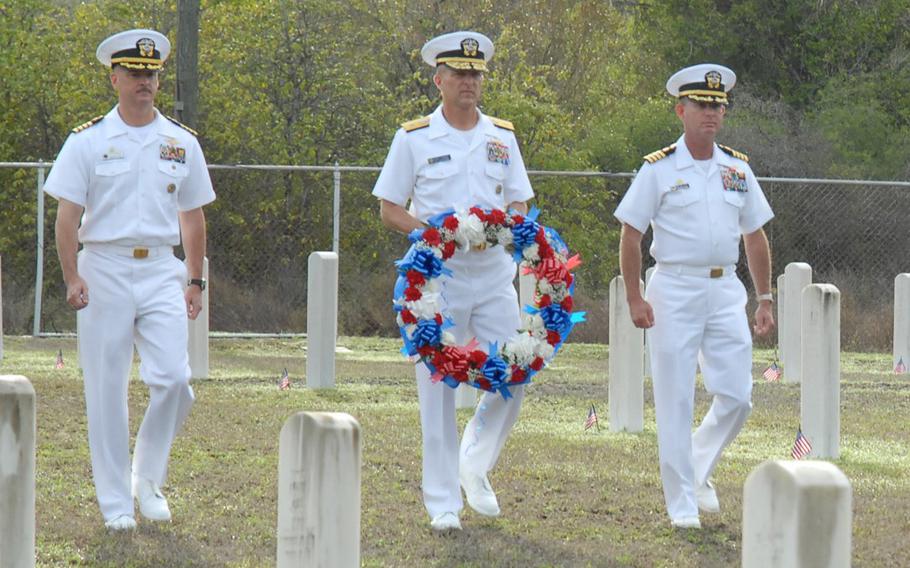 Navy Capt. Bruce Meneley, then-Guantanamo Bay Navy Hospital commanding officer, far right, with Navy Capt. Steven Blaisdell, U.S. Naval Station Guantanamo Bay commanding officer, far left, and Navy Rear Adm. Dave Thomas, Joint Task Force Guantanamo commander, middle, place a Memorial Day wreath at Cuzco Wells Cemetery, Guantanamo Bay, Cuba, May 25, 2009.