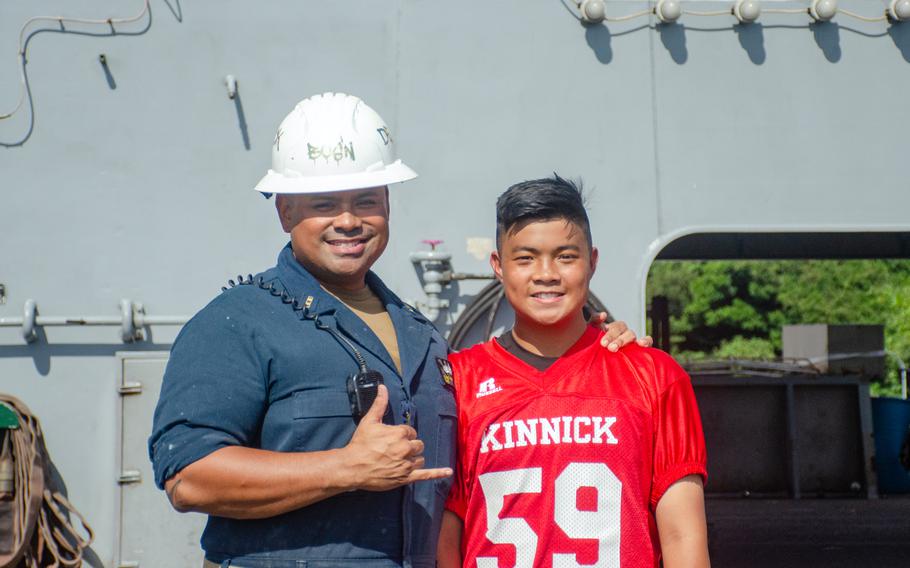 A member of the Nile C. Kinnick High School football team poses with his father aboard the aircraft carrier USS Ronald Reagan at Yokosuka Naval Base, Japan, Tuesday, Sept. 12, 2023.