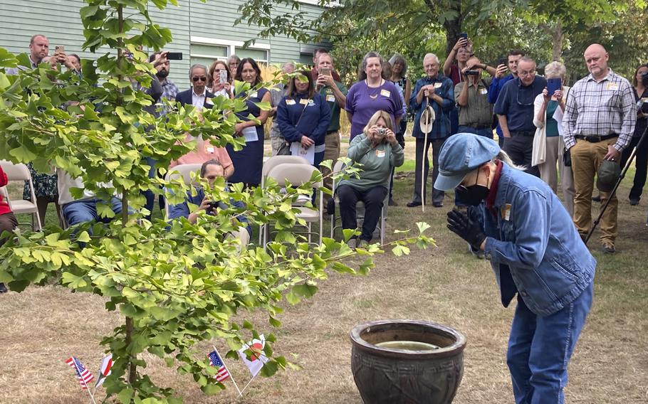 Hideko Tamura Snider, a survivor of the atomic bombing of Hiroshima, Japan, bows on Wednesday, Sept. 21, 2022, in Salem, Ore, before watering a ginkgo tree that came from a seed of a tree that also survived the bombing. Tamura Snider, who was 10-years-old when her city was destroyed by the atomic bomb and who now lives in Medford, Ore., was the guest of honor at a ceremony marking the culmination of a four-year-long campaign in Oregon to plant saplings grown from the seeds of trees that survived the atomic bombing of Hiroshima.