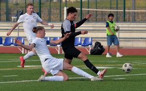 Kelan Vaughn of Ramstein slides in to separate Stuttgart’s Seth Harpuder from the ball in the Division I boys final at the DODEA-Europe soccer championships in Ramstein, Germany, May 22, 2025. Ramstein took the title with a 2-0 win.