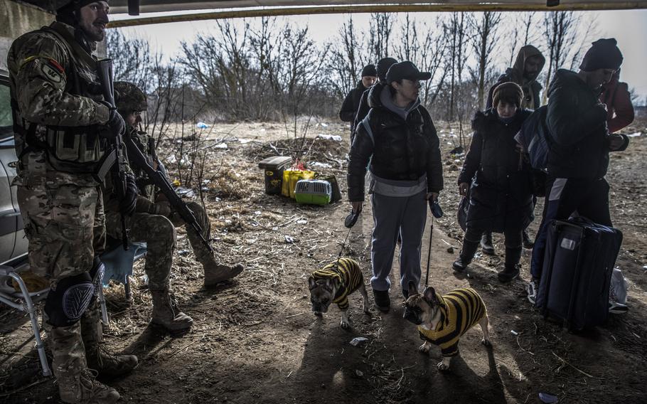 A family with their two dogs arrive at a damaged bridge as they flee Irpin on March 12.