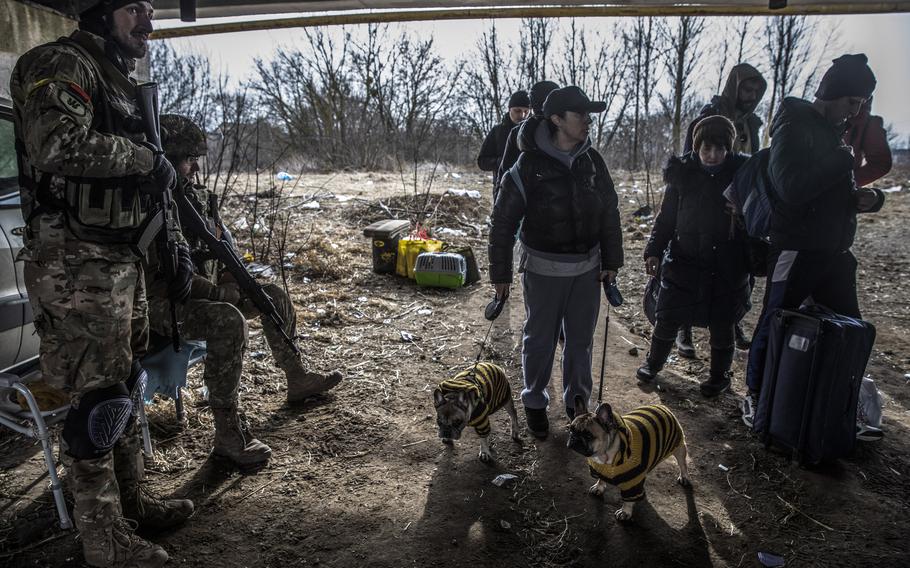 A family with their two dogs arrive at a damaged bridge as they flee Irpin on March 12.