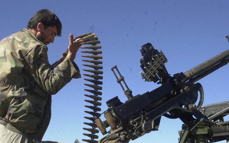 A Northern Alliance fighter loads his heavy machine gun as the opposition forces prepare to move towards a Taliban pocket south of Kabul, Nov. 24, 2001.