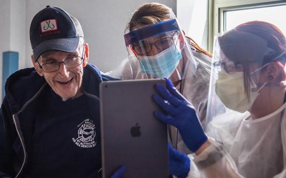 U.S. Army veteran Skip, left, uses an iPad to speak to his family with the help of nurse manager Laurie Nicol, center, and recreation therapist Kristen Weber at Holyoke Soldiers Home in Holyoke, Mass., where he was in isolation due to COVID-19, April 20, 2020. Using technology to connect with others during coronavirus lockdowns and quarantines is thought to be one reason why suicidal thoughts among veterans fell during the pandemic, says a study published August 25, 2021.
