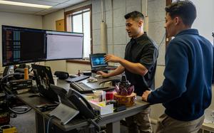 Two airmen working at a computer.