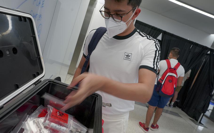 Sam Avila, a first-year graduate student, submits a viral test sample at George Washington University. Coronavirus testing is an entry requirement for the campus.