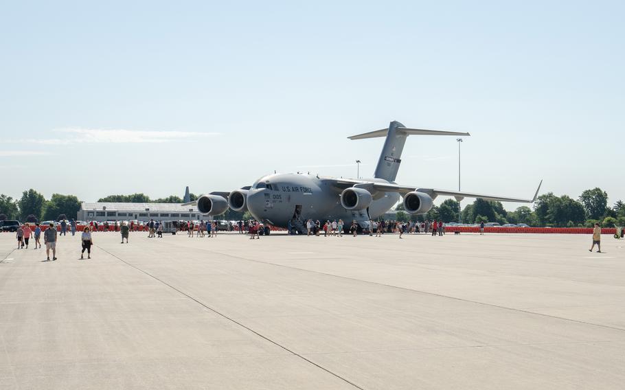 People walk around an aircraft on a military base.
