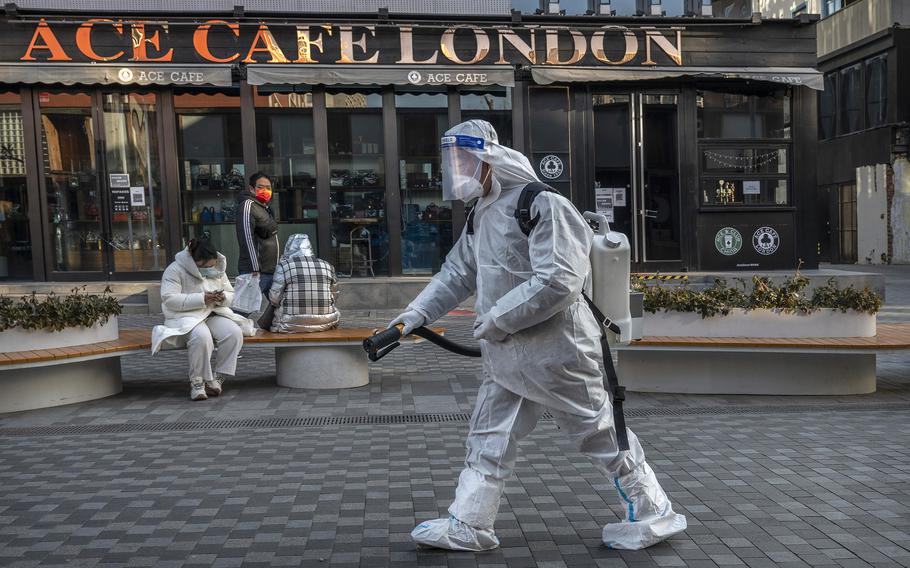 An epidemic control worker wears PPE as he sanitizes a pedestrian shopping area on Dec. 8, 2022, in Beijing.