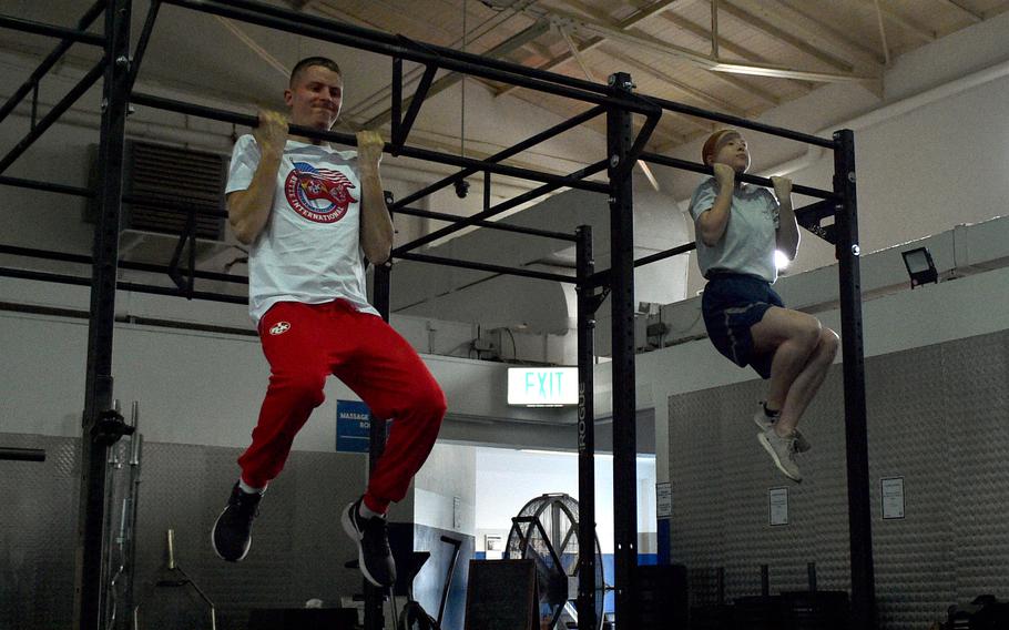 1. FC Kaiserslautern midfielder Aaron Basenach, left, and Airman Emma Gantner, who earned a German armed forces badge for military proficiency last year, compete in the flexed-arm hang, March 23, 2023, at Northside Gym on Ramstein Air Base, Germany. It was part of the soccer team's tour of the base.