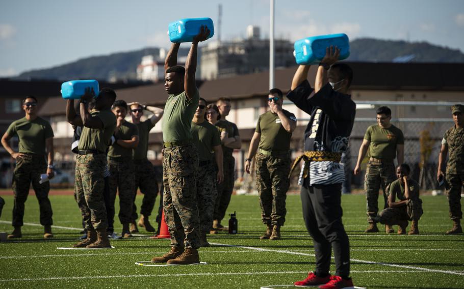 Marine Cpl. Darrion Thompson, 23, of Chicago, center, the eventual winner, lifts a water jug during a Sports Day weightlifting challenge on Marine Corps Air Station Iwakuni, Japan, on Oct. 28, 2022.