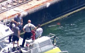 Firefighters and others in a boat speak to each other.