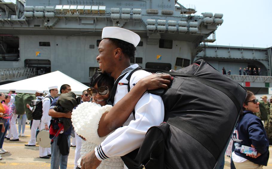 A sailor is wrapped in an embrace by a loved one