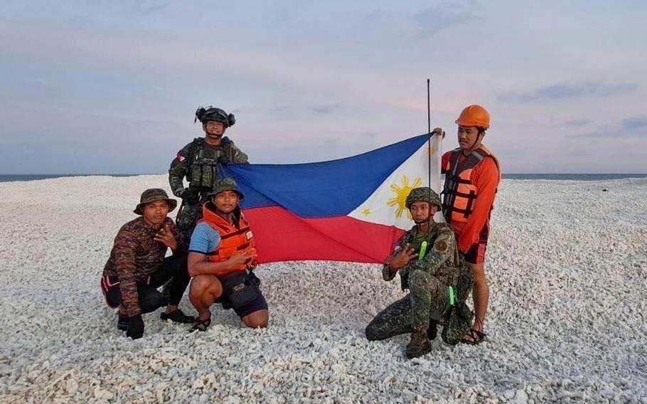 Philippine inter-agency members including Philippine navy, Philippine coast guard and Philippine national police members, hold the Philippine flag as they visit a sandbar.
