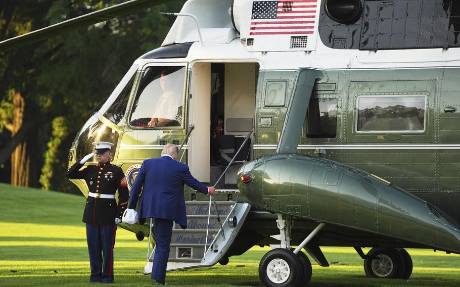 President Donald Trump in a blue suit, beginning to walk up the steps of Marine One.