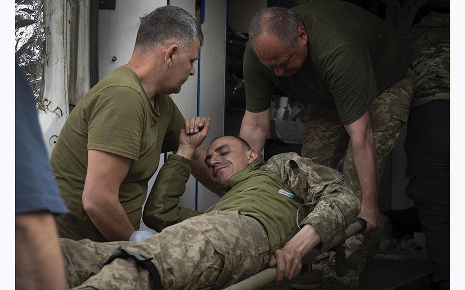 Ukrainian soldiers carry their wounded fellow at a medical stabilisation point near Bakhmut, Donetsk region, Ukraine, on Wednesday, May 24, 2023.