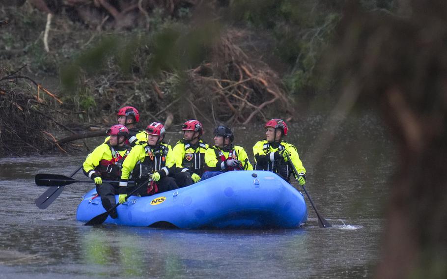 Rescuers in life jackets and helmets row in a blue boat on the river.