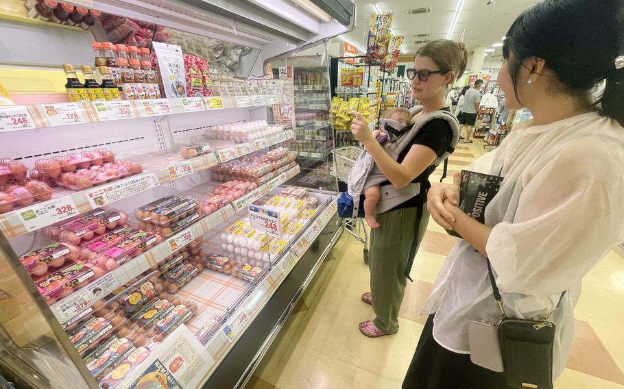 A member of the Japanese American Society shops with a Marine Corps spouse, who is carrying a baby, at a Japanese grocery store.