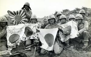 Ten Marines pose with Japanese “good luck” flags in a black and white picture from 1945.