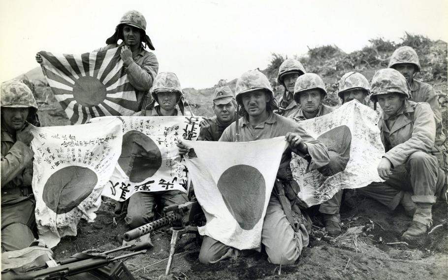 Ten Marines pose with Japanese “good luck” flags in a black and white picture from 1945.