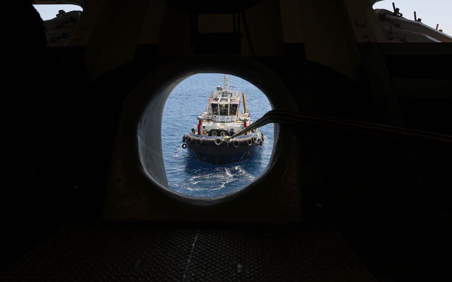A tugboat positioned in front of the ship’s forecastle assists in maneuvering the amphibious assault ship USS Wasp into Souda Bay, Greece.