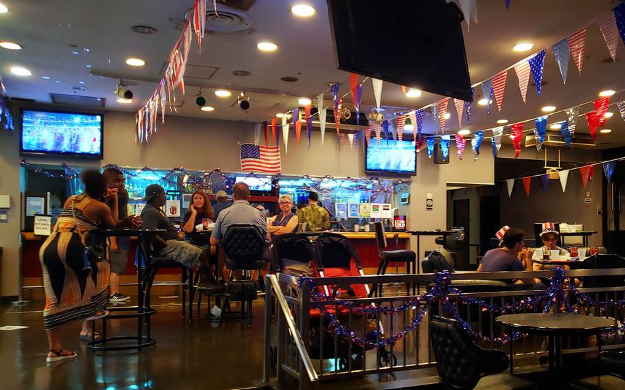 Sailors gather at Club Alliance at Yokosuka Naval Base, Japan, to watch the Tokyo Olympics' opening ceremony, Friday, July 23, 2021.