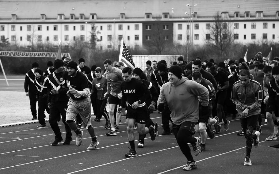 A black and white photo of people running on a race track.