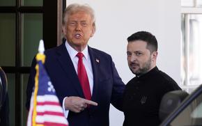 Donald Trump stands next to and points at Volodymyr Zelenskyy outside an entrance to the White House.