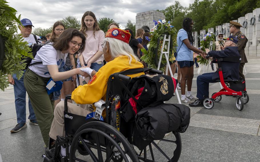 Veterans in wheelchairs shaking hands with people.