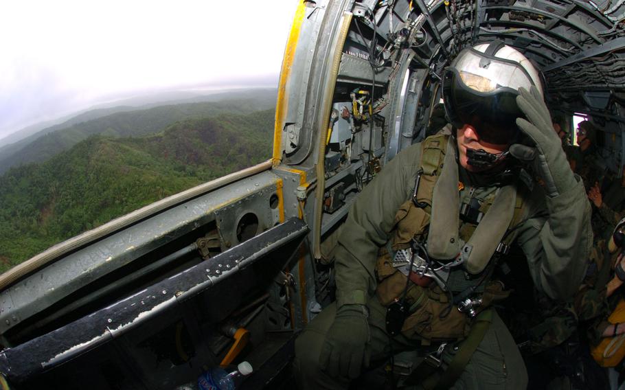 Staff Sgt. James McGuiness from Marine Medium Helicopter Squadron-262 pulls down his visor to view the bright landscape while flying relief supplies.