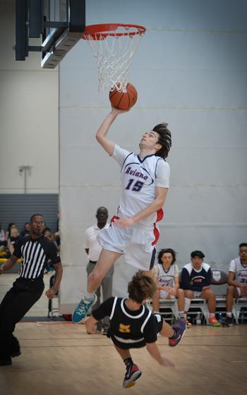 Aviano’s Gabe Fabbro knocks Bahrain’s Jesse Bakke to the ground as he leaps for a layup at the DODEA-Europe Division II boys basketball tournament Wednesday, Feb. 15, 2023.